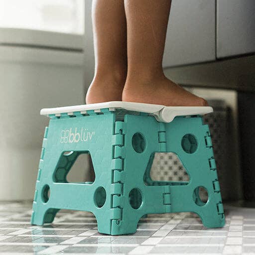 Teal folding step stool with a person using it in a kitchen.