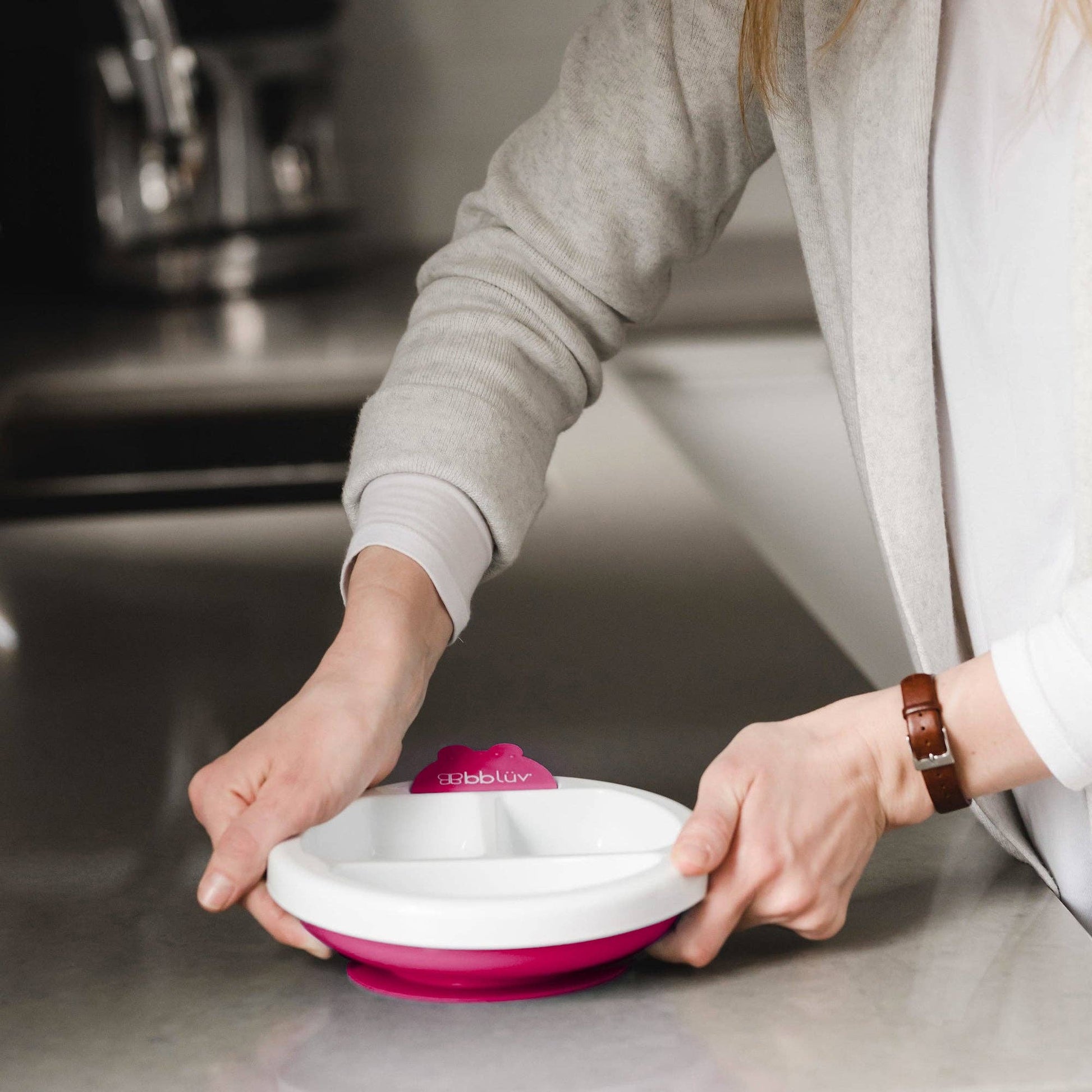 Person holding a pink and white plate on a kitchen counter