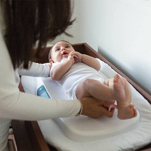 Baby lying on a changing table with a person's hand holding its foot