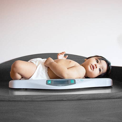 Baby lying on a digital baby scale with a white background