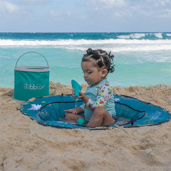 Child playing on a blue sandcastle building kit at the beach with a bbluv bucket.