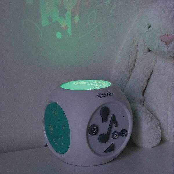 Children's night light with music player functions on a shelf next to a teddy bear.