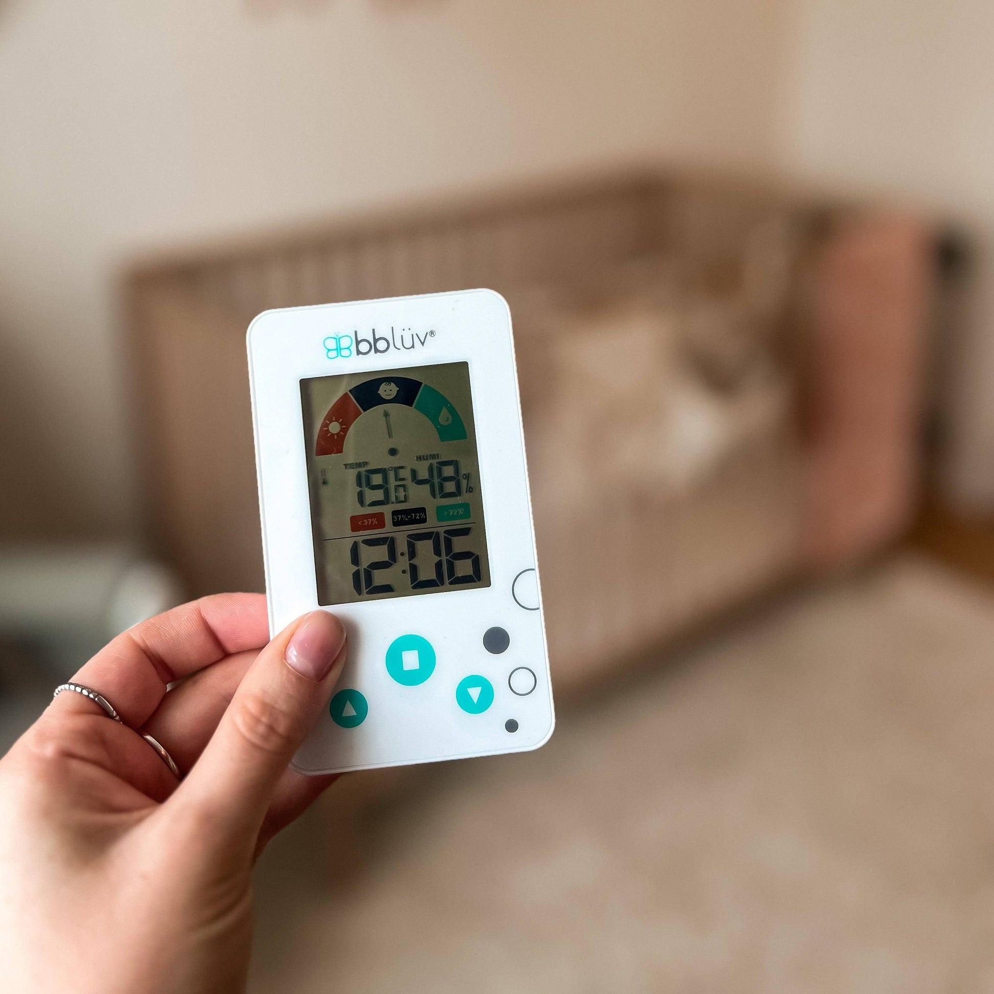 Hand holding a digital thermometer with a blurred indoor background 1