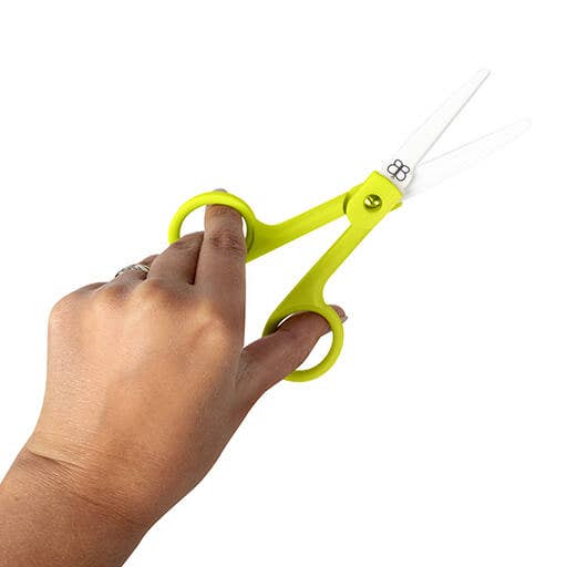 Hand holding a pair of bright yellow scissors on a white background