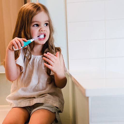 Young girl brushing her teeth in a bathroom.